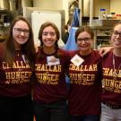 Students pose in a line in kitchen, all wearing burgundy T-shirts with &ldquo;Challah for Hunger UC Davis&rdquo; in gold.