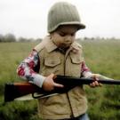 Photo: little boy in a cap holding a rifle