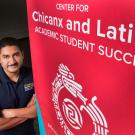 Cirilo Cortez by a banner for the Center for Chicanx and Latinx Academic Student Success