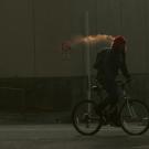 Bicyclist's breath condenses into what looks like a cloud or fog.