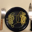 place setting with scissors, knives and a plate of spaghetti