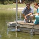 Professor John Eadie and student Jody Deal drop a dredging device into the arboretum waterway. It was one method they used to gather flora samples for their duck study.  