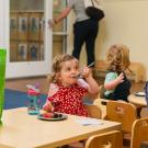 Girl eats cake at table in child care center.