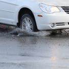 Car splashes tire in pothole