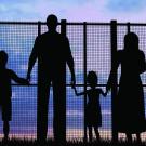 Silhouette of family staring through fence