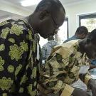 Two men in colorful African shirts lean over a counter