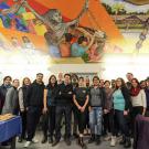 Students, faculty and staff pose under a mural.