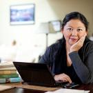 Photo: Yiyun Li at laptop computer, resting chin in hand