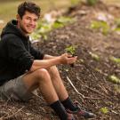 A male student sits on a compost pile.