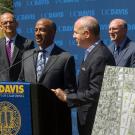 Gary S. May and Darrell Steinberg at podium adorned with UC Davis banner (with seal)