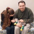 A man and woman hold a cat with bandaged paws.