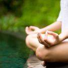 Woman in peaceful meditation pose crossing legs and with thumbs touching forefinger