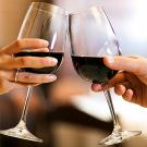 Hands of couple toasting with glasses or red wine.
