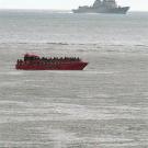 Photo: Whale fins in foreground, with boat and ship in middle and background on ocean