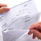 Hands pull paper paycheck from envelope.