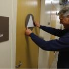 Photo: Worker installed gender-inclusive sign to restroom door.