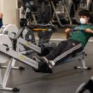 Man wearing face covering uses rowing machine at the ARC.