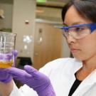 Selina Wang peers at olive oil in beaker, in lab.