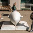 Students (blurred) walking past "Bookhead" sculpture (in focus).