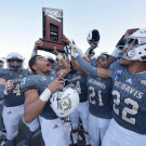 Aggie football team holds up Big Sky Conference trophy.