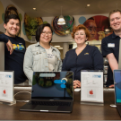 Four employees pose behind computer display.