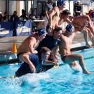 Water polo team jumps into pool, in celebration.