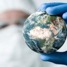 Researcher holds small world in gloved hand