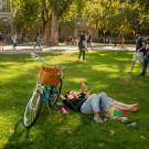 Student On Grass Next to Bike