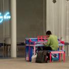 A man in a green shirt plays the piano outside the Manetti Shrem museum.