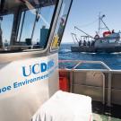 Boat deck with UC Davis Tahoe Environmental logo and a research vessel on a blue lake