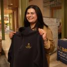 Audirana holds up a sweatshirt with the new logo of what is now known as the Undocumented Student Resource Center