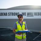 UC Davis plant scientist Alessandro Ossola in safety vest and cap holding clipboard in front of Altadena Strong banner. (Jael Mackendorf/ UC Davis)