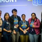 Students from previous Biz Quiz pose with awards in front of Biz Quiz backdrop