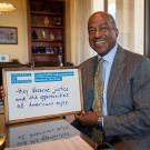 Photo of chancellor Gary S. May holding a white board that says "I stand with undocumented students because: They deserve justice and the opportunities all Americans enjoy."