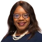 Smiling woman with glasses and pearl necklace, studio headshot on white background