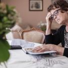 Woman sitting at dining table pondering bills