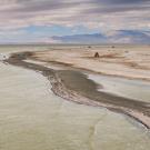 drone image of Salton Sea waters going up to dry lakebed with mountains in distance