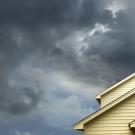 storm clouds hover over top of cream-colored home