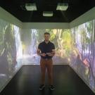 Julien Delarue, associate professor in sensory science, stands in the immersive room. He's surrounded by 3 walls showing video of woods and waterfalls.