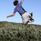 Teen jumps with joy by gray willows in Arctic