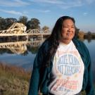 Pam Bulahan iin sweater and t-shirt stands with Sacramento River behind her