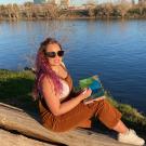 Rachael Dal Porto with sketchbook on log by Sacramento River