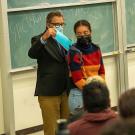 A professor puts a symbolic card into a student's backpack during a demonstration