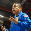Jose Hernandez in blue NASA uniform with Cesar Chavez event poster in background