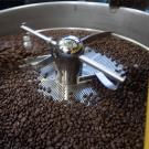 A silver-colored machine turns coffee beans in a circle.