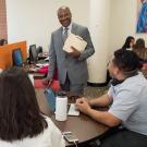 Chancellor Gary S. May, in suit and tie, stands while chatting with students at a round table, in academic success centerh students