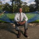 Chancellor Gary S. May, in shirt and tie, seated on hammock, on the Quad.