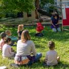 Children sit in circle for class held outdoors.