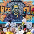 Children place flowers in front of mural dedicated to George Floyd.