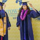 Graduate students wearing graduation regalia move their tassles. 